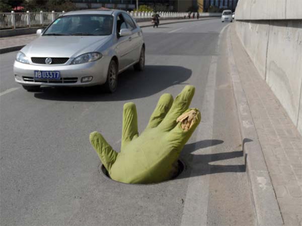 Giant green hand reaches out of manhole to remind drivers of danger