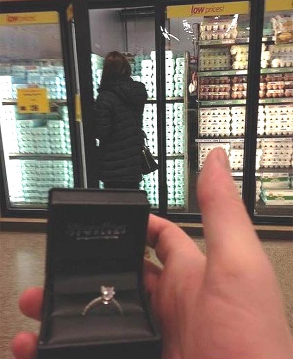 Man Taking Pictures with Engagement Ring and His Would-Be Fiance in the Background