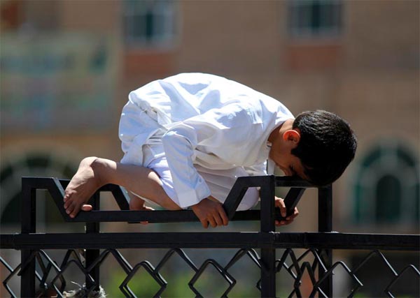 Boy Performing Prayer on Fence