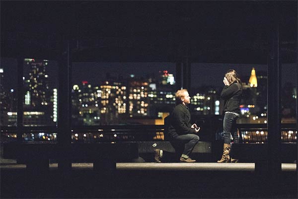 Man Taking Pictures with Engagement Ring and His Would-Be Fiance in the Background