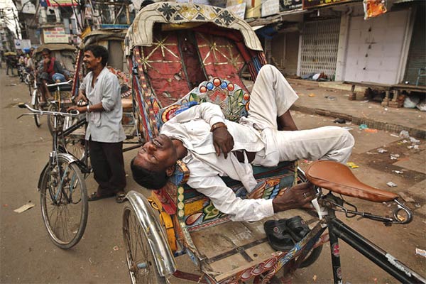 Indian rickshaw puller sleeps on his rickshaw