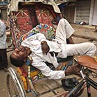 Indian rickshaw puller sleeps on his rickshaw
